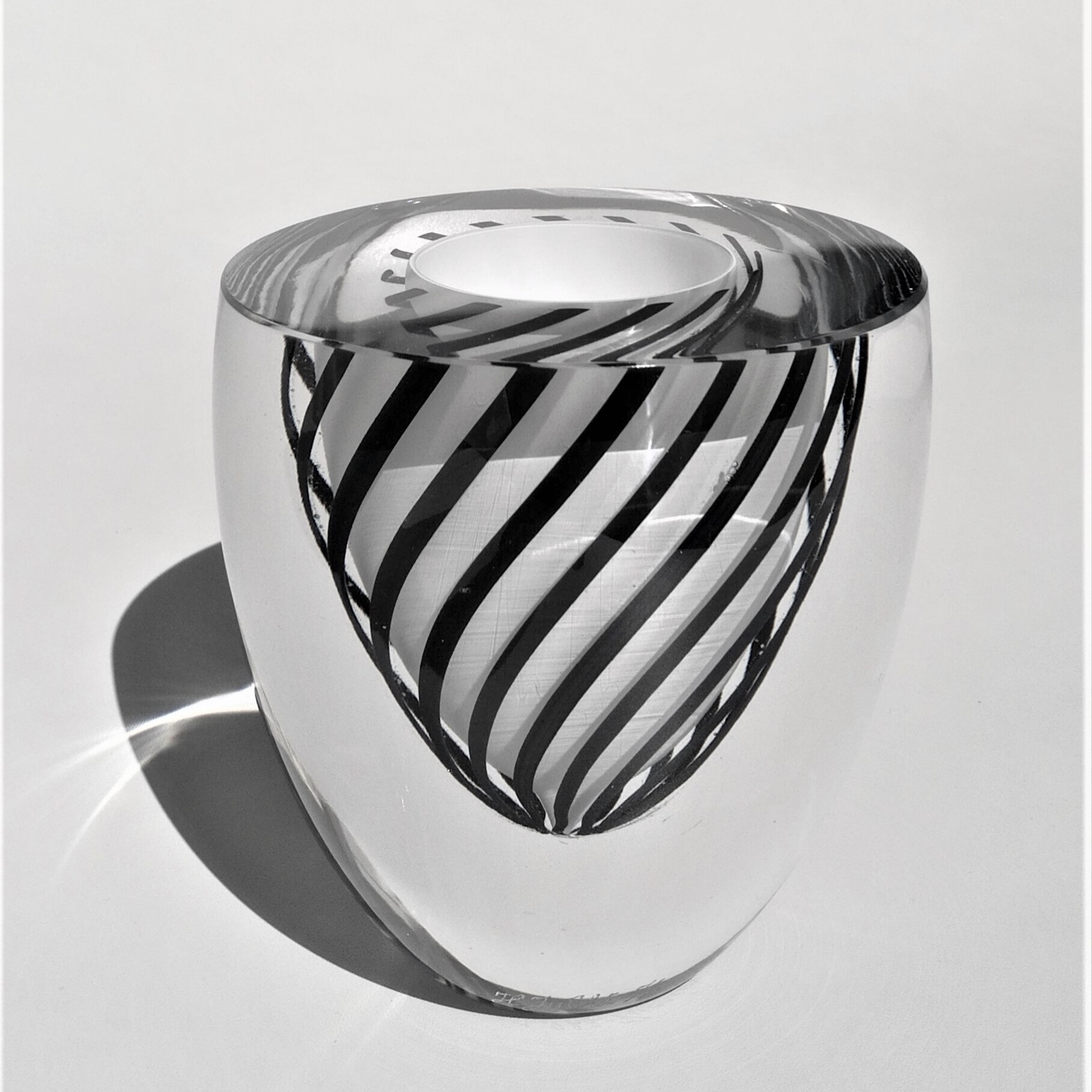 Mustavalkoinen, puhallettu optinen uniikkilasi, jonka reuna on katkaistu ja hiottu. Koristelu on tehty filigraanitekniikalla. Heikki Jylhä-Vuorio.